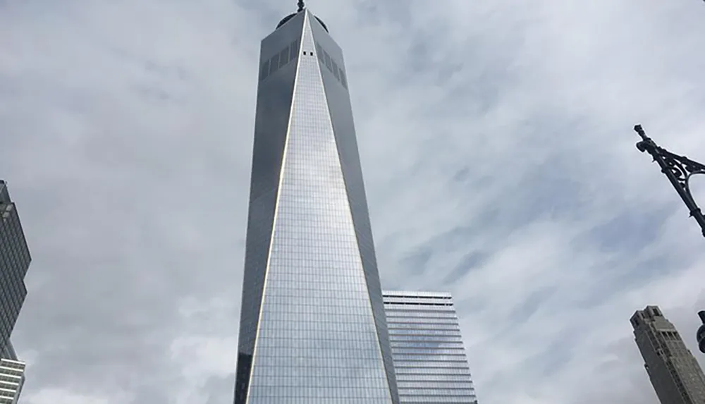 The image showcases the towering facade of a reflective glass skyscraper against an overcast sky