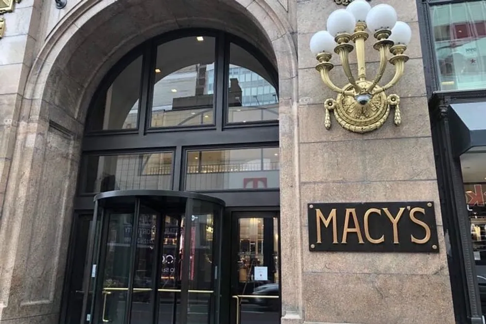 The image shows the exterior of a Macys department store with a distinctive arch and gold-colored signage