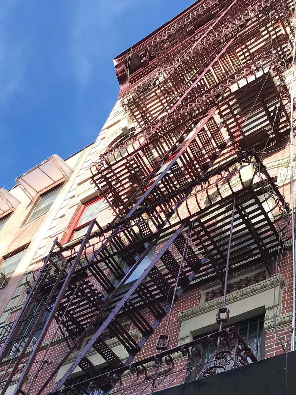 The image shows a multistory building with intricate fire escapes against a blue sky