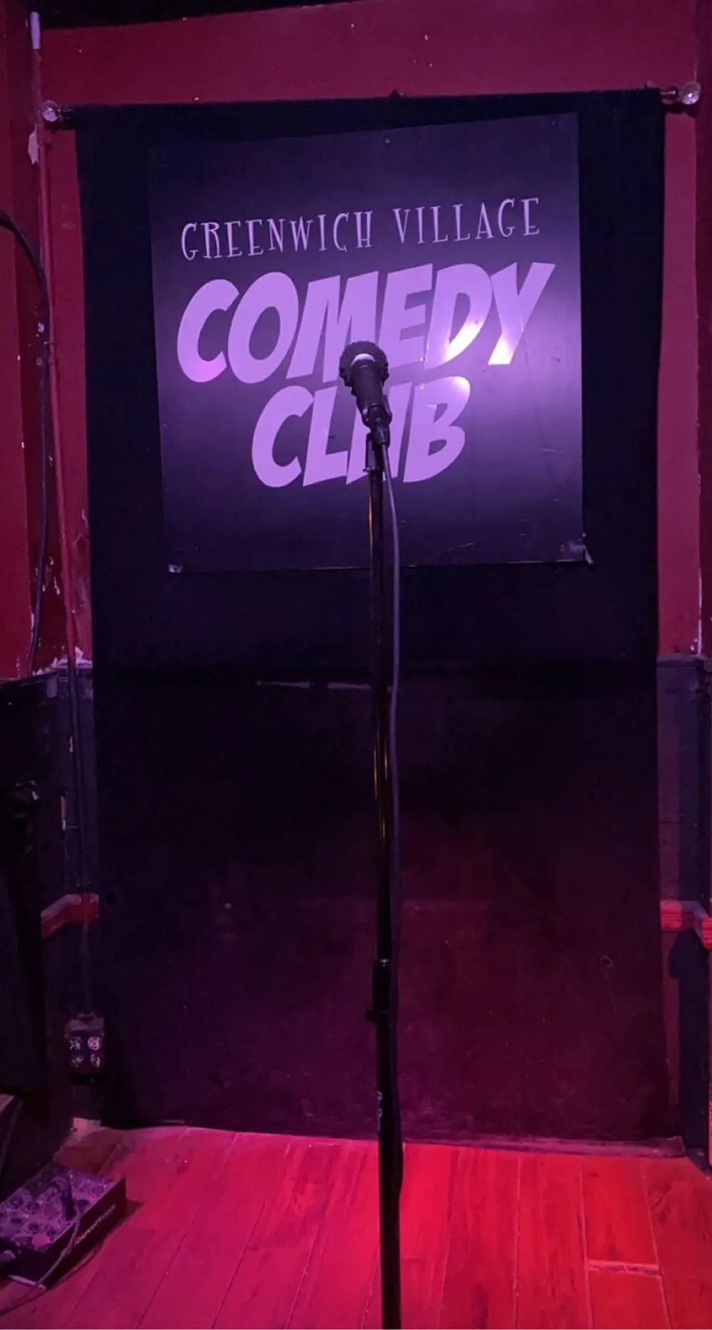 A stage with a microphone awaits a performer at the Greenwich Village Comedy Club under a spotlight