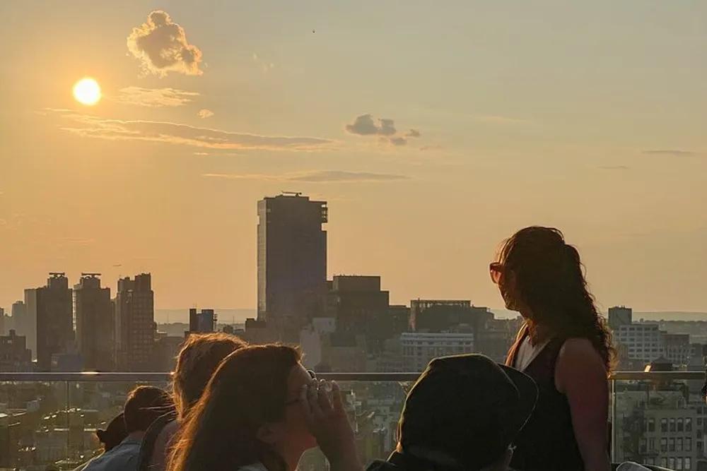 This image captures a group of people enjoying a scenic sunset over a city skyline