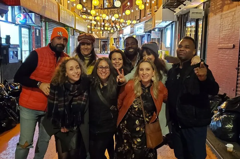 A group of happy people are posing together for a photo on a festive lantern-lit street at night