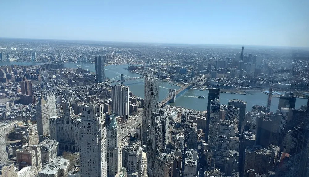 The image shows a high-altitude view of a dense urban skyline with skyscrapers a river and bridges captured on a clear day