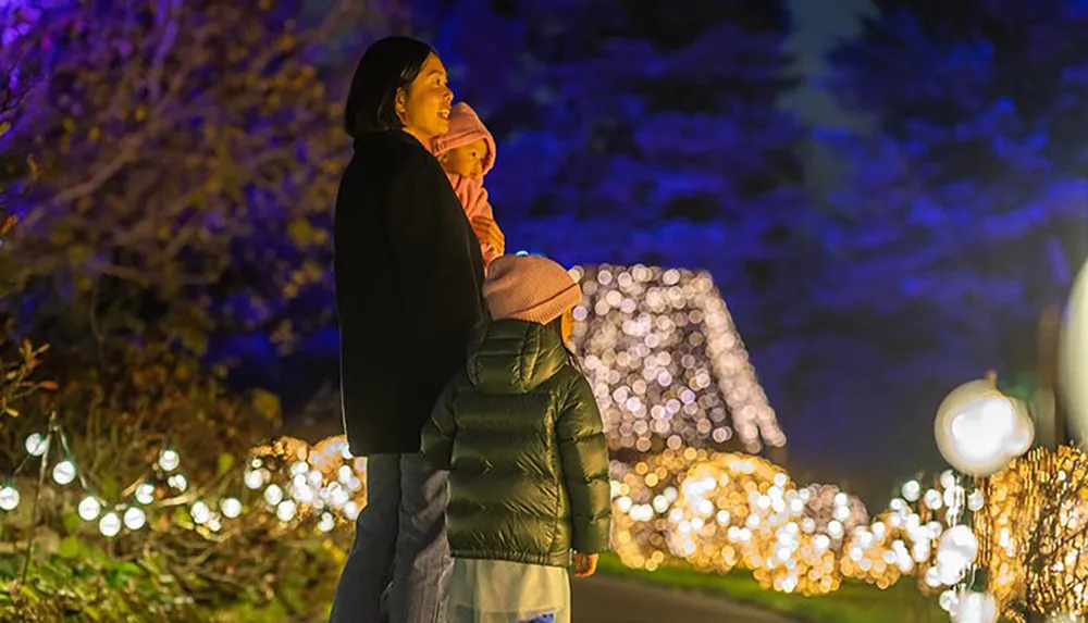 A woman and a child enjoy a nighttime illumination event gazing at the vibrant lights that adorn the parks surroundings