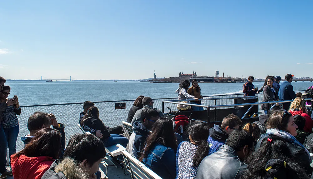 Passengers on a ferry enjoy the view including the Statue of Liberty and Ellis Island on a clear day