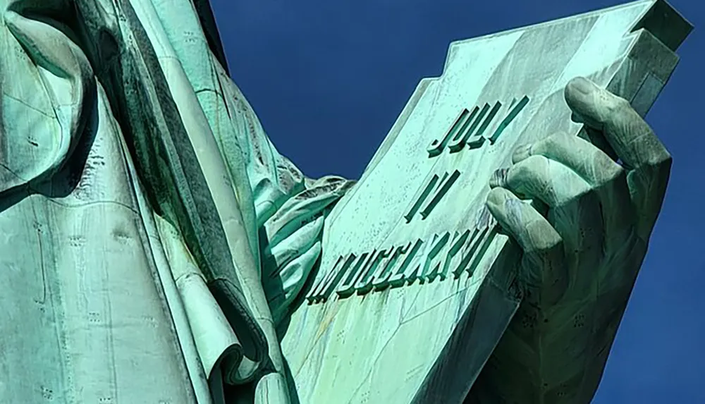 The image shows a close-up of the Statue of Libertys hand and tablet with the date JULY IV MDCCLXXVI inscribed on it symbolizing the American Declaration of Independence on July 4 1776
