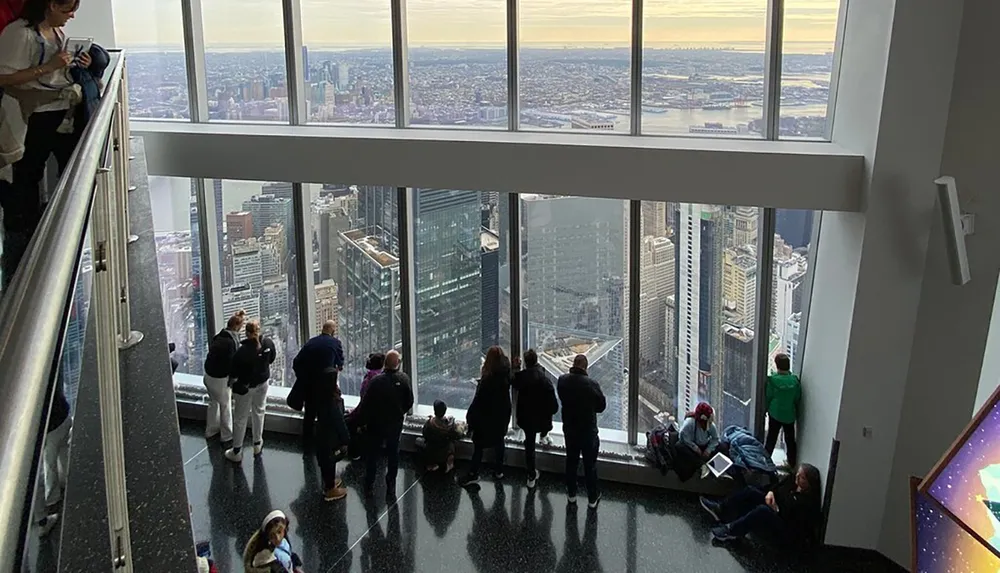 Visitors are enjoying a panoramic view of the city from a high vantage point with large windows